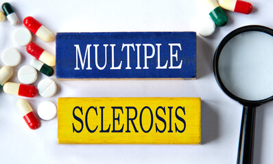 MULTIPLE SCLEROSIS - words on a wooden blue block on a background of pills