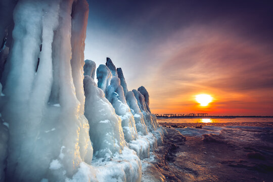 Wooden posts of an old pier covered in ice in Baltic Sea at sunset, Sventoji, Lithuania