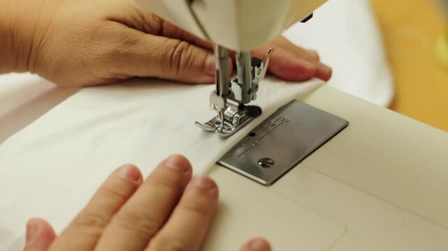 cosiendo una tela blanca en una m&aacute;quina de coser el&eacute;ctrica, taller de costura