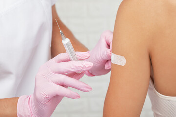 Young woman getting injection against coronavirus at hospital. Healthy lifestyle concept.
