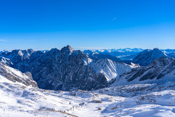 Stunning aerial panorama view of snow covered peaks of Austrian Alps in Tyrol from Zugspitzplatt on a sunny day with blue sky and cloud in winter, Garmisch-Partenkirchen, Bavaria, Germany