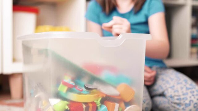 Beautiful child girl cleans up her toys. Little girl tydies up her room.