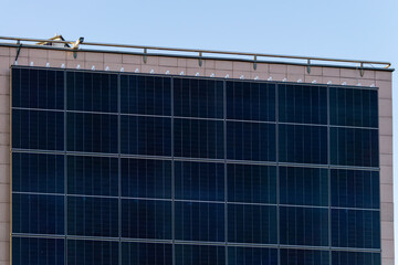 photovoltaic panels, solar panels hanging vertically on the wall of a building in the city.