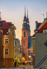 Obraz premium urban landscape at sunset, illuminated city and church in the distance. interesting architecture and construction in the old town of Opole