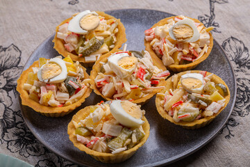 Salad with crabs and pineapples in tartlets on a plate decorated