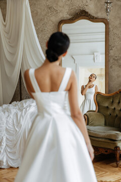 Photo from behind posing of a sexy beautiful girl in a white dress with a long train. Tender portrait of a girl