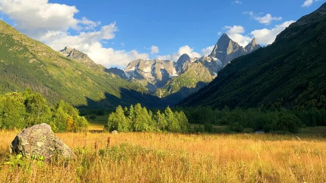 Teberdinsky Nature Reserve. View of Kosygin's glade in the Gonachkhir gorge and the top of Dombai-Ulgen mountain near Lake Tumanly-Kel on a sunny summer day. Panoramic landscape. Resort. 4K
