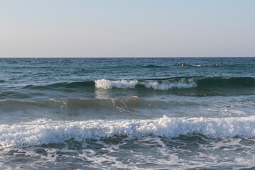 Beach of luxury hotel. sunny day, windy, stormy, wavy sea, blue sky. On the beach shines soft yellow-gold brown-golden sand. Sea waves crashing on the shore with wavy white foam. on island of cyprus
