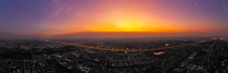 view of sunset city skyline, transportation with cars on Expressway, Road, Roundabout, multilevel junction highway-Top view. Important infrastructure, cloudscape, cityscape, building, crane.
