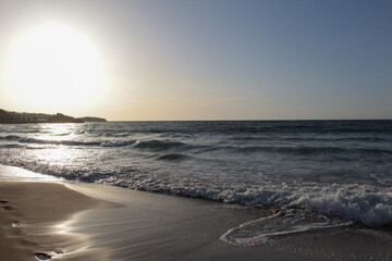 Beach of luxury hotel. sunny day, windy, stormy, wavy sea, blue sky. shines soft yellow-gold brown-golden sand with sunsets. Sea waves crashing on the shore with wavy white foam. on island of cyprus. 