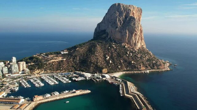 Calpe Spain 4k drone of Penon de Ifach mountain cliff. Panoramic panning view revealing modern city skyline beachfront resort skyscrapers sand coast and Mediterranean sea b-roll