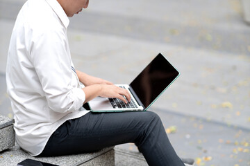 Business man in casual clothes is sitting and using laptop on lap