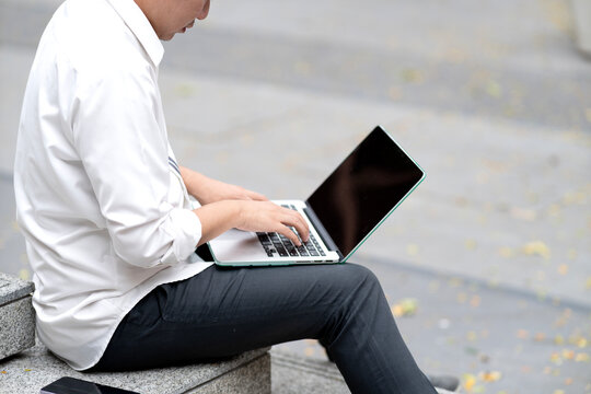Business man in casual clothes is sitting and using laptop on lap
