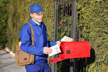 Postman putting parcel into mail box outdoors