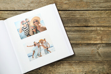 Different photos in open photo album on wooden table, top view. Space for text