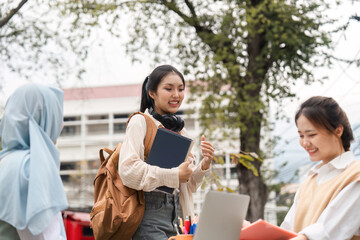 Diverse female student with headphones engaging in discussion with peers outdoors.