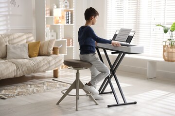 Little boy playing synthesizer at home. Electronic musical instrument © New Africa