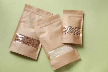 Paper pouch bags with different products on green background, top view