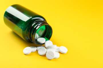 Medical bottle with antibiotic pills on yellow background, closeup. Space for text