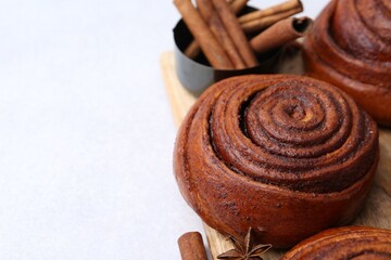 Delicious cinnamon roll buns on light table, closeup. Space for text