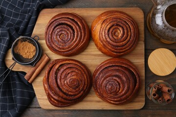 Delicious cinnamon rolls, sticks and powder on wooden table, flat lay