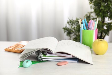 Doing homework. Notebook with math assignment, apple and stationery on white desk. Space for text