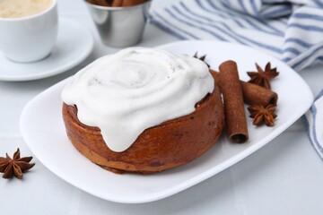 Tasty cinnamon roll with cream, spices and coffee on white table, closeup