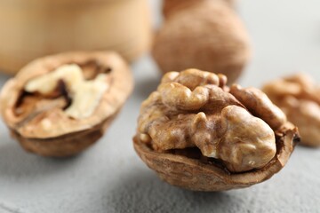 Fresh walnuts with shells on gray table, closeup. Space for text