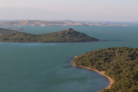 Magnificent trees swaying on a hot, windy summer day. railing, view from railing of sea, islands, foggy, cloudy, sky, as the sun sets. Devil's Table (Devil's Table) Balikesir, Sarimsakli, T&uuml;rkiye