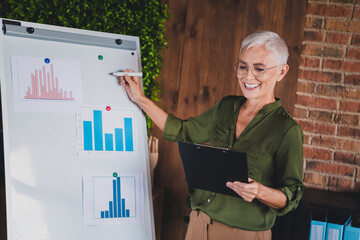 Photo of cheerful lovely lady assistant dressed shirt presenting graphics indoors workplace...