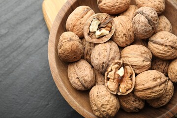 Fresh walnuts in shells on black table, top view. Space for text