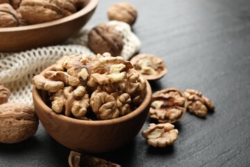 Fresh ripe walnuts and shells on black table, closeup. Space for text