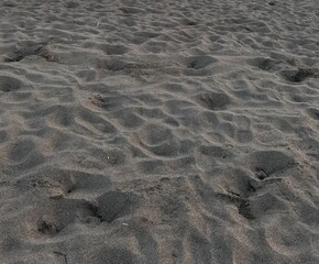 Close-up of textured sandy beach with small footprints and natural patterns