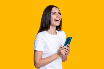 Naklejka premium Millennial laughing woman blogging on phone or using communication chat on smartphone isolated on yellow