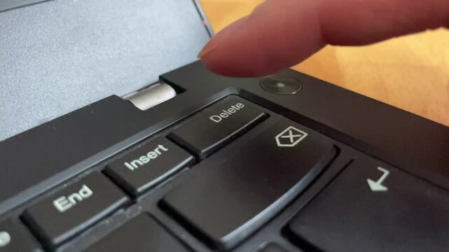 Closeup of a finger aggressively pressing the delete button on a keyboard on laptop