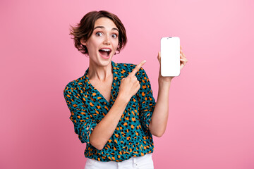 Photo of excited attractive girl dressed stylish shirt directing at smartphone screen empty space...