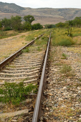 Fototapeta premium Railroad tracks by the mountains, vertical picture