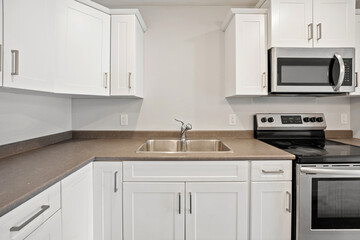 Fototapeta premium A clean and empty kitchen with a white stove and microwave