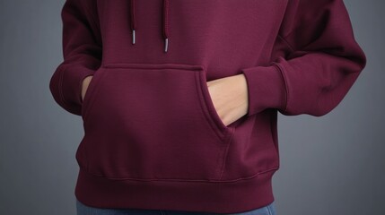 Close-up of woman's hands in maroon hoodie pocket.