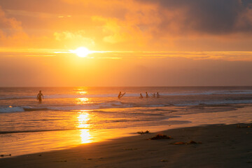 Dramatic sunset on the beach with surfers