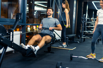 Muscular man does heavy weight exercise for back on machine with cable. © Mediteraneo