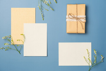 Composition with two blank sheets of paper and gift box on blue background. Flat lay, top view.