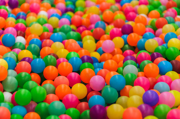 Background of many mixed plastic colored and multicolored round balls in children's playroom for kids to play. Photography, childhood concept, abstract.