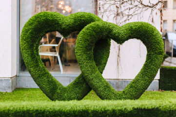 Two hearts made of artificial grass on the lawn stand in the park outdoors. Photo, symbol of love.
