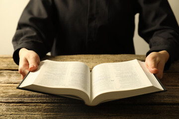 Woman with Holy Bible in English language at wooden table, closeup