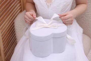 Bride opening beautiful wedding gift indoors, closeup