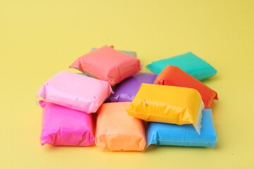 Different colorful play dough in packages on yellow background, closeup