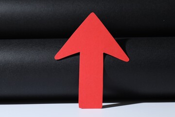 One red paper arrow on color background, closeup