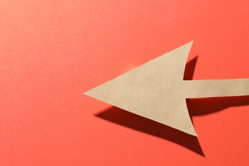 One kraft paper arrow on red background, top view. Space for text