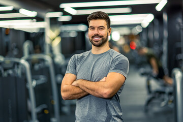 Muscular fitness man standing with his arms crossed in the gym.